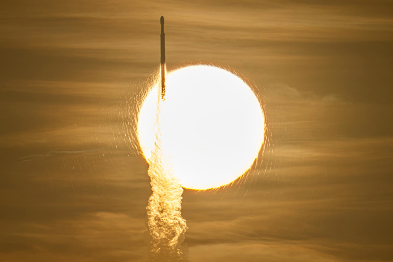 A SpaceX Falcon Heavy with NASA's Roman Space Telescope transiting the rising Sun, captured by photographer John Kraus during the August 30, 2026 launch from Kennedy Space Center Launch Complex 39A. (NASA/John Kraus source image)